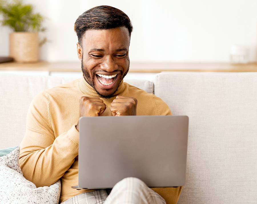 Website Coaching One-on-One für Heilpraktiker Junger Mann lacht begeistert am Laptop – Symbol für erfolgreiches 1:1 Website-Coaching