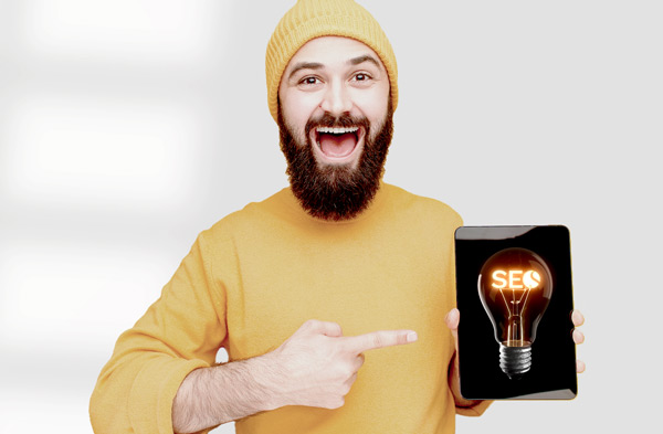 Mann zeigt auf Tablet mit leuchtender Glühbirne als Symbol für SEO-Coaching und Sichtbarkeit für Heilpraktiker